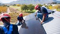 Mitarbeiter installieren Solarpanele auf einem Dach in Südafrika