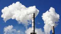 Smoking industrial chimneys against blue sky
