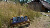Solarkollektoren stehen in Afrika auf einer Bank mit einer Hütte im Hintergrund. 