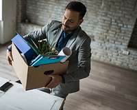 Geschäftsmann verlässt Büro mit gepackter Kiste