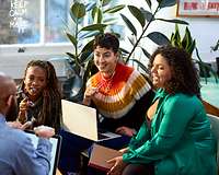 Gruppe von Frauen und Männern, divers, im Gespräch vor einem Laptop