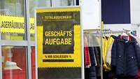 Schild "Geschäftsaufgabe" vor einem Kleidergeschäft