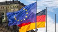 Die EU- und die deutsche Flagge wehen vor dem Reichstag