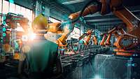 Ingenieur an einer KI-gesteuerten Fertigungsstraße mit Roboterarmen