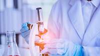 Biotechnik Laborantin untersucht Proben durch ein Mikroskop