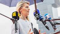 Ursula von der Leyen spricht in Mikrofone verschiedener Medienhäuser