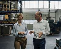 Junge Frau und älterer Mann in Fabrikhalle