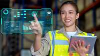 Junge Mitarbeiterin in Warnweste arbeitet am Tablet