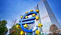 Großes Euro-Zeichen steht vor gläsernen Gebäuden in Frankfurt