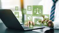 Mann tippt auf einem Laptop, darüber schweben Icons