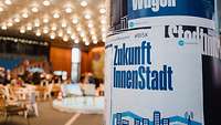 Plakatierte Litfasssäule mit dem Spruch "Zukunft Innenstadt" beim Innenstadtkongress 2024