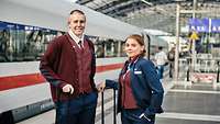 Zwei junge Menschen in Schaffner-Uniform stehen am Bahngleis