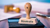 Holzstempel steht auf einem Stempelkissen und trägt die Aufschrift "Bürokratie"