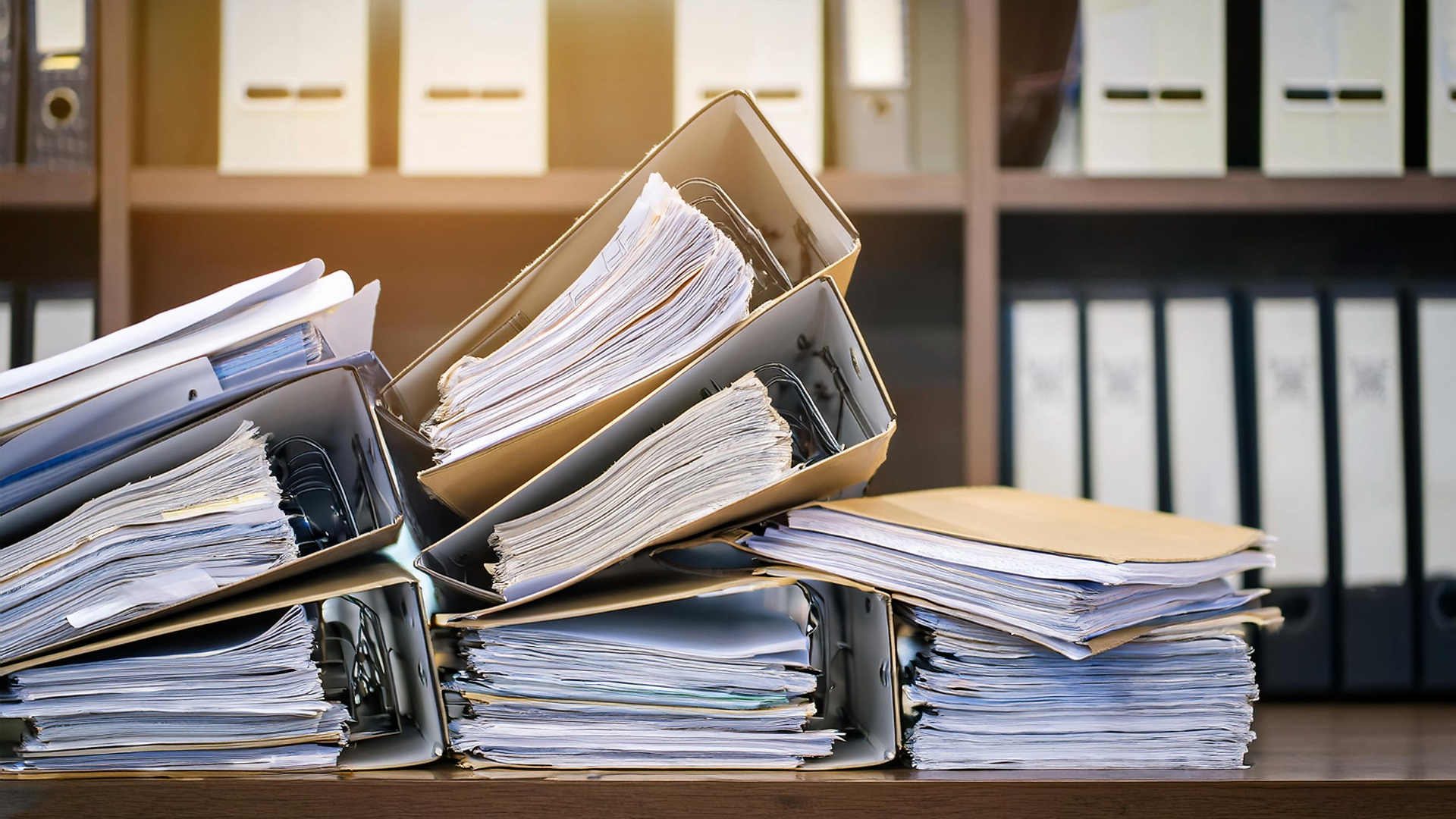 Ordner und Papiere stapeln sich auf einem Schreibtisch