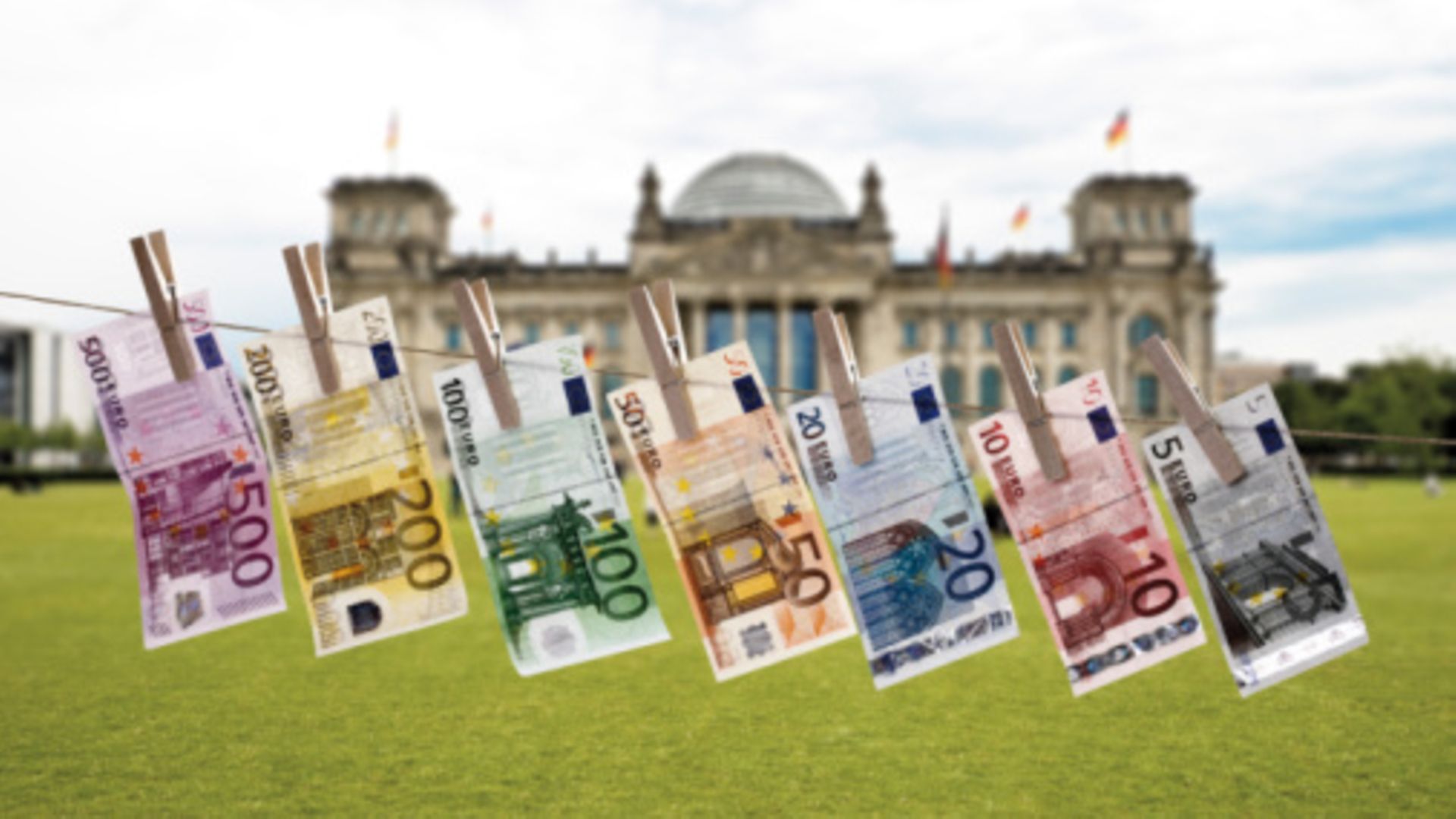 Geldscheine hängen an einer Wäscheleine vor dem Reichstagsgebäude