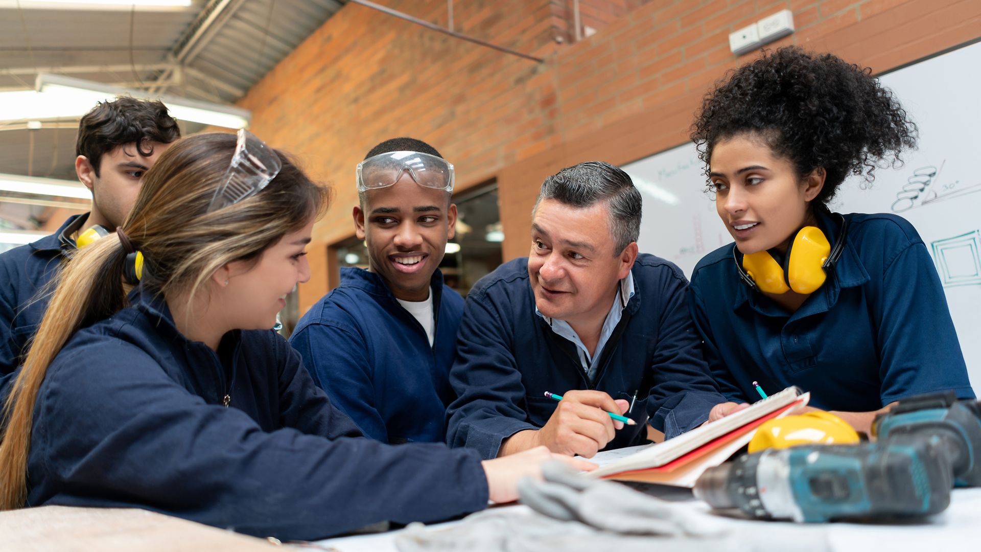 Multiethnische Gruppe Azubis schart sich um einen Ausbilder