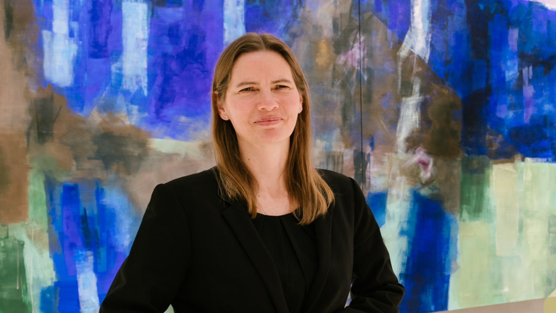 Frau steht vor Gemälde.