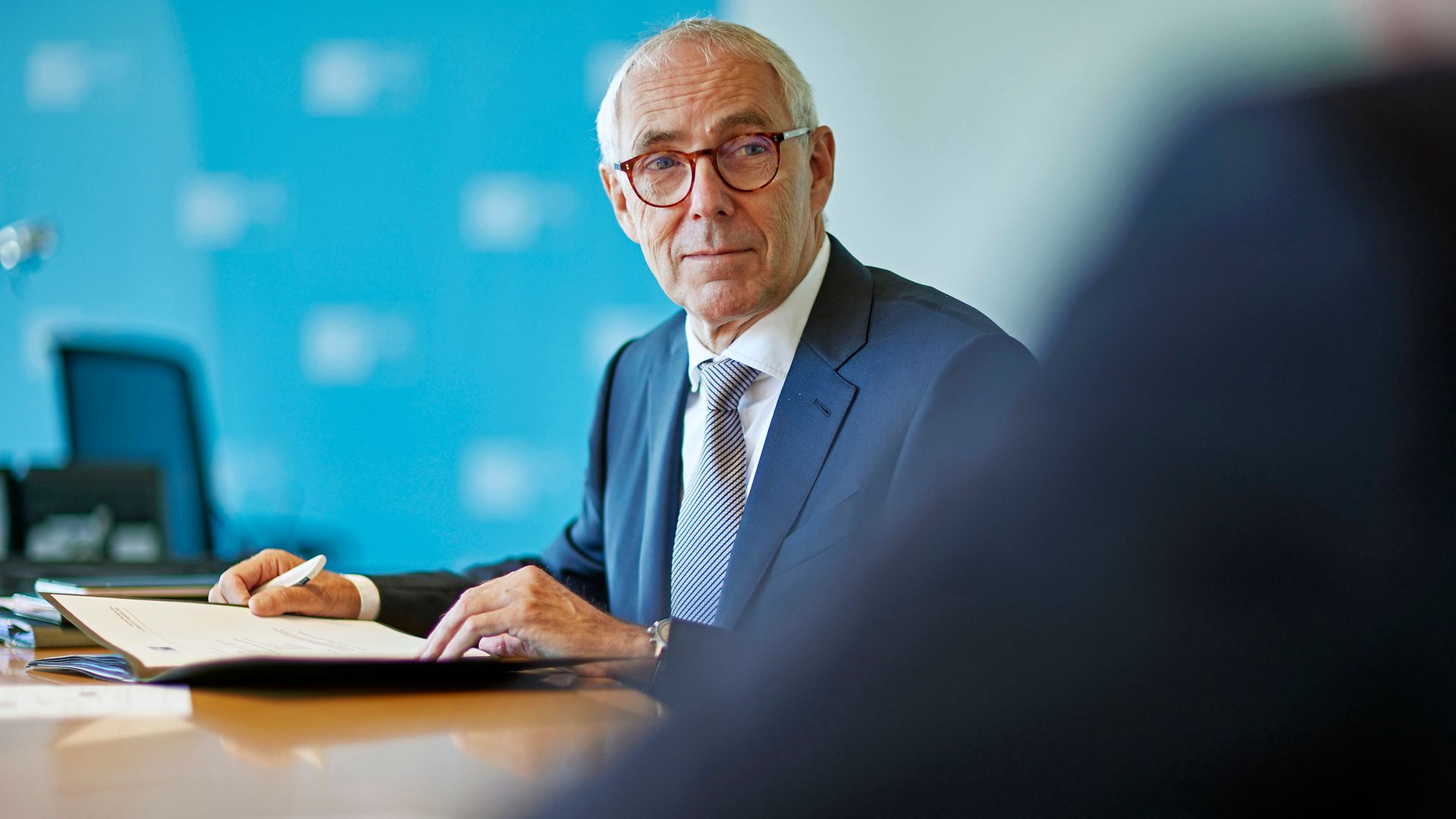 Peter Adrian sitzt an einem Tisch mit einem geöffneten Dokument