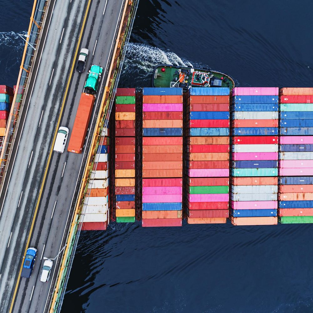 Beladenes Containerschiff unterquert Brücke mit LKW