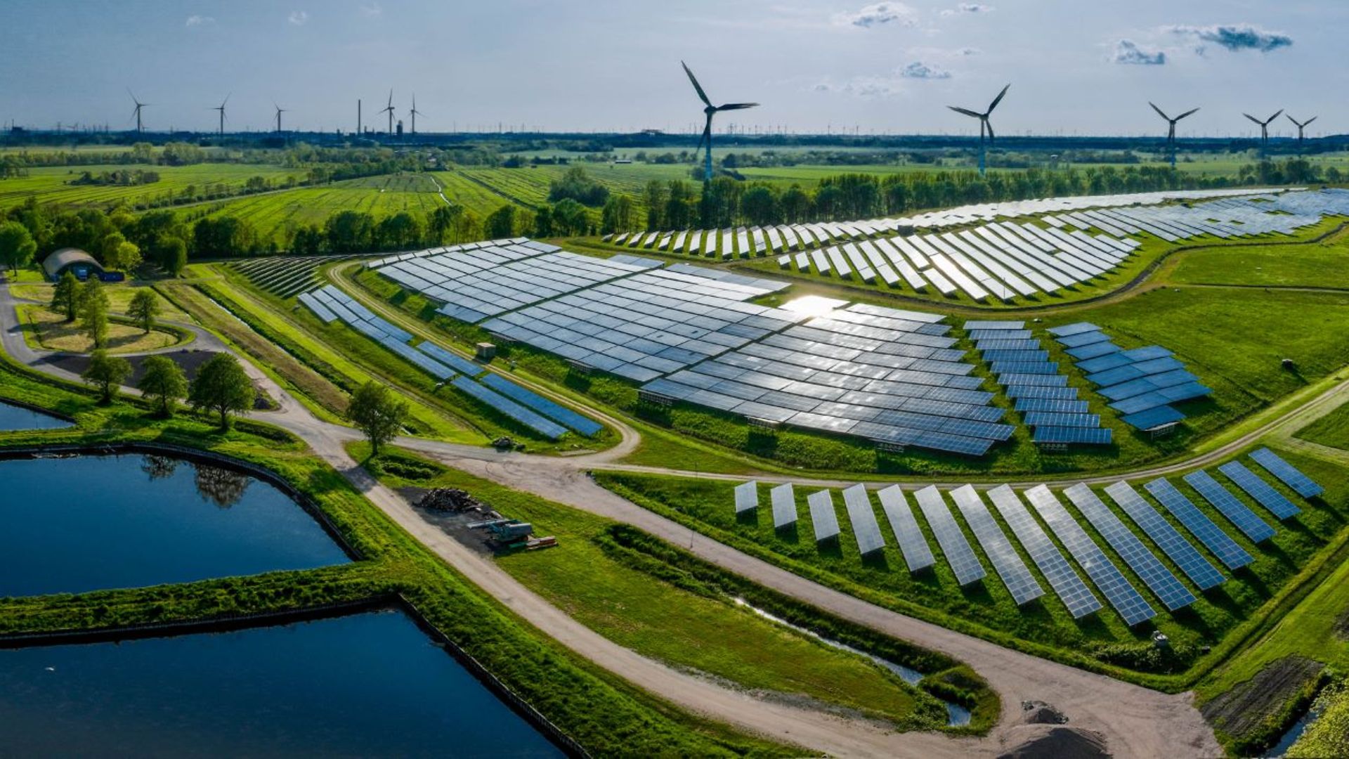 Ein Feld mit Solarpanels und Windrädern