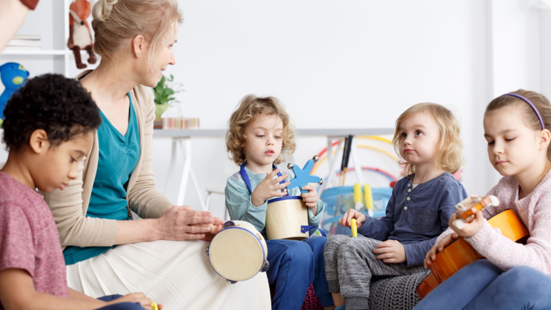 Kinderbetreuung: Eine Erzieherin spielt mit vier kleinen Kindern