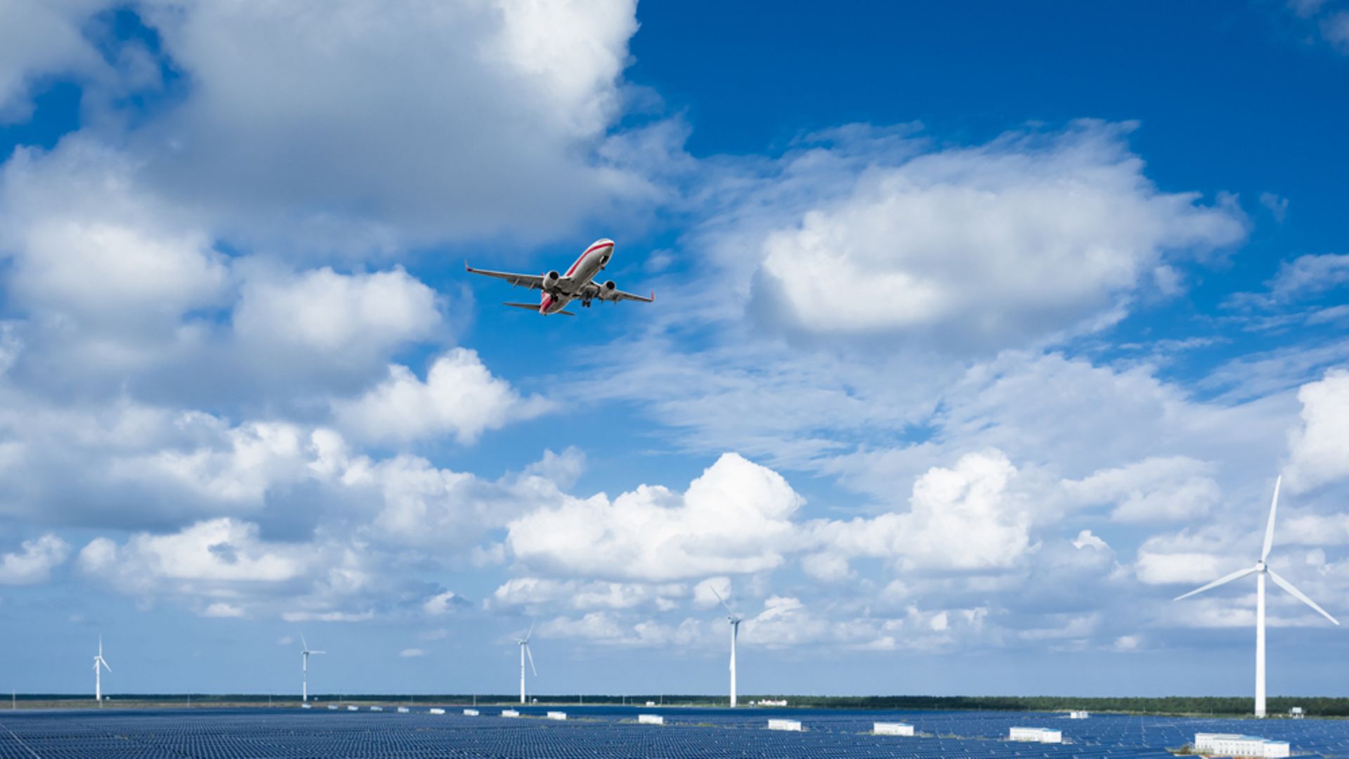 Flugzeug über Solarfarm mit Windrädern