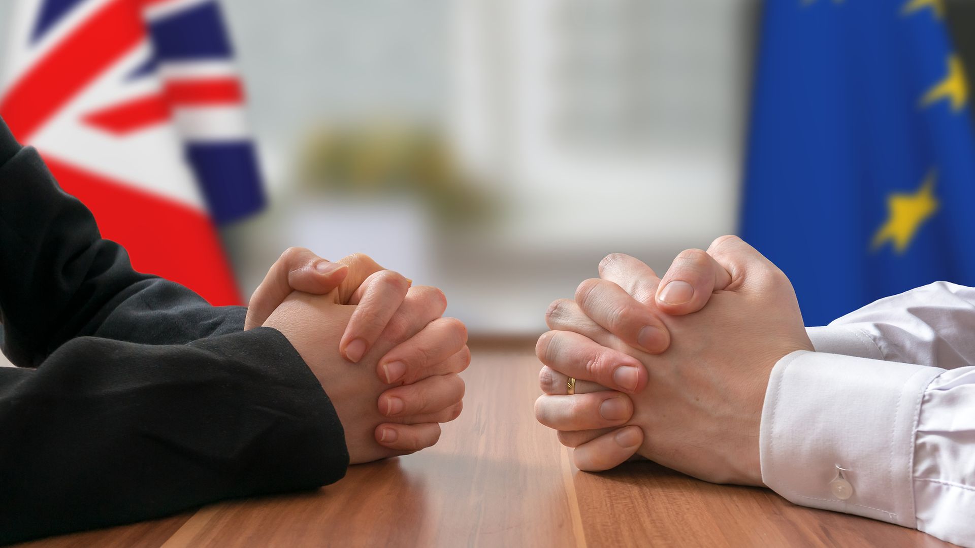 gefaltete Hände vor Union Jack und EU-Flagge