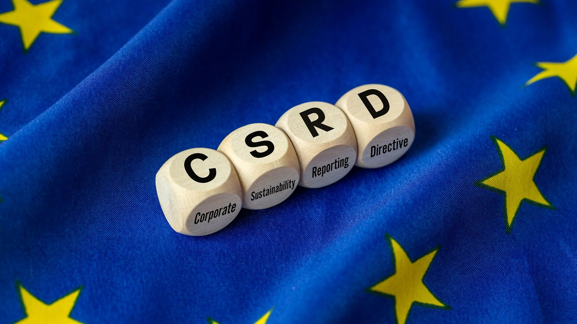 Vier Würfel mit "C", "S", "R" und "D" liegen auf einer EU-Flagge