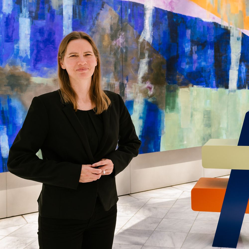 Frau steht vor Gemälde.