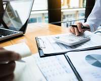 Charts, Geschäftspapiere und Taschenrechner auf einem Schreibtisch