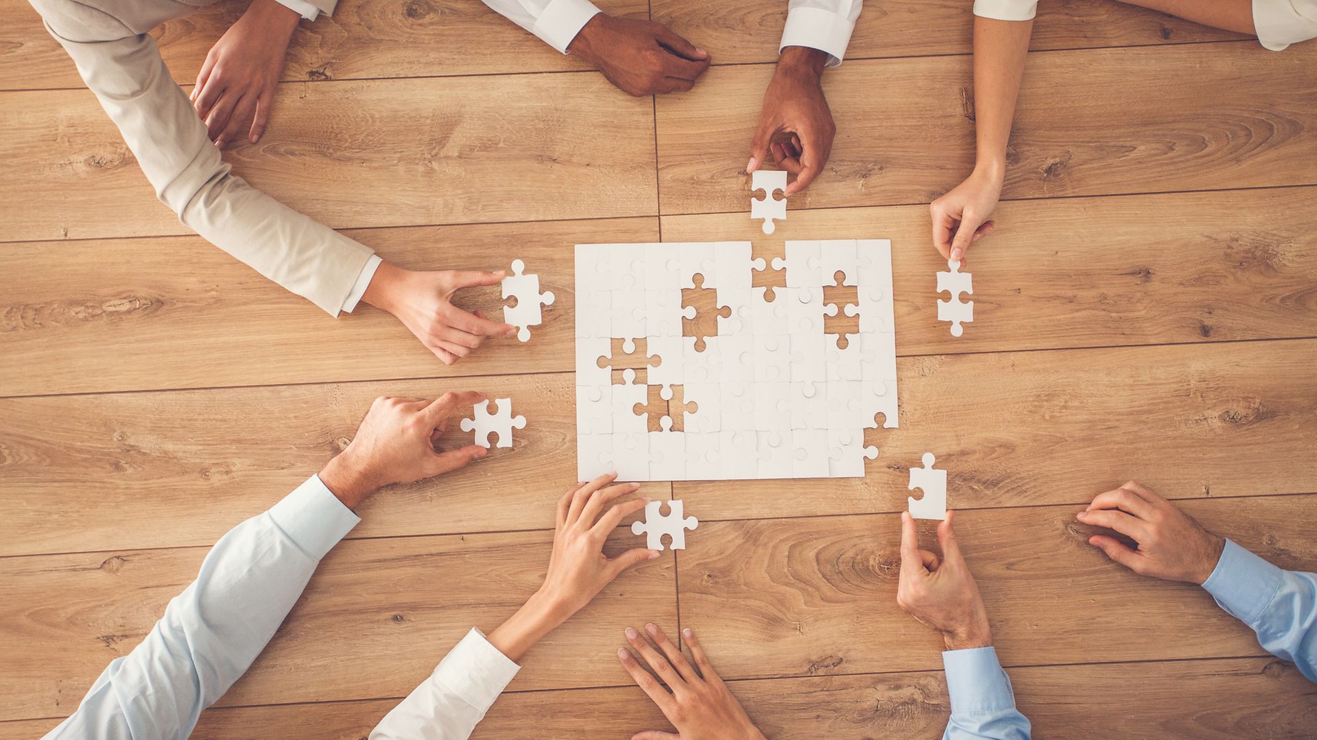 Puzzleteile und Hände auf Tisch