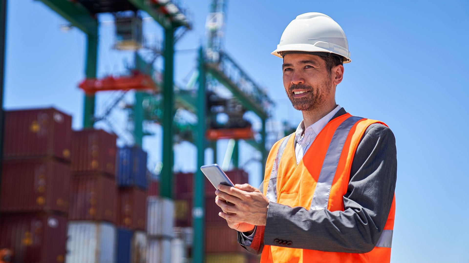 Zollbeamter mit Handy vor Containern