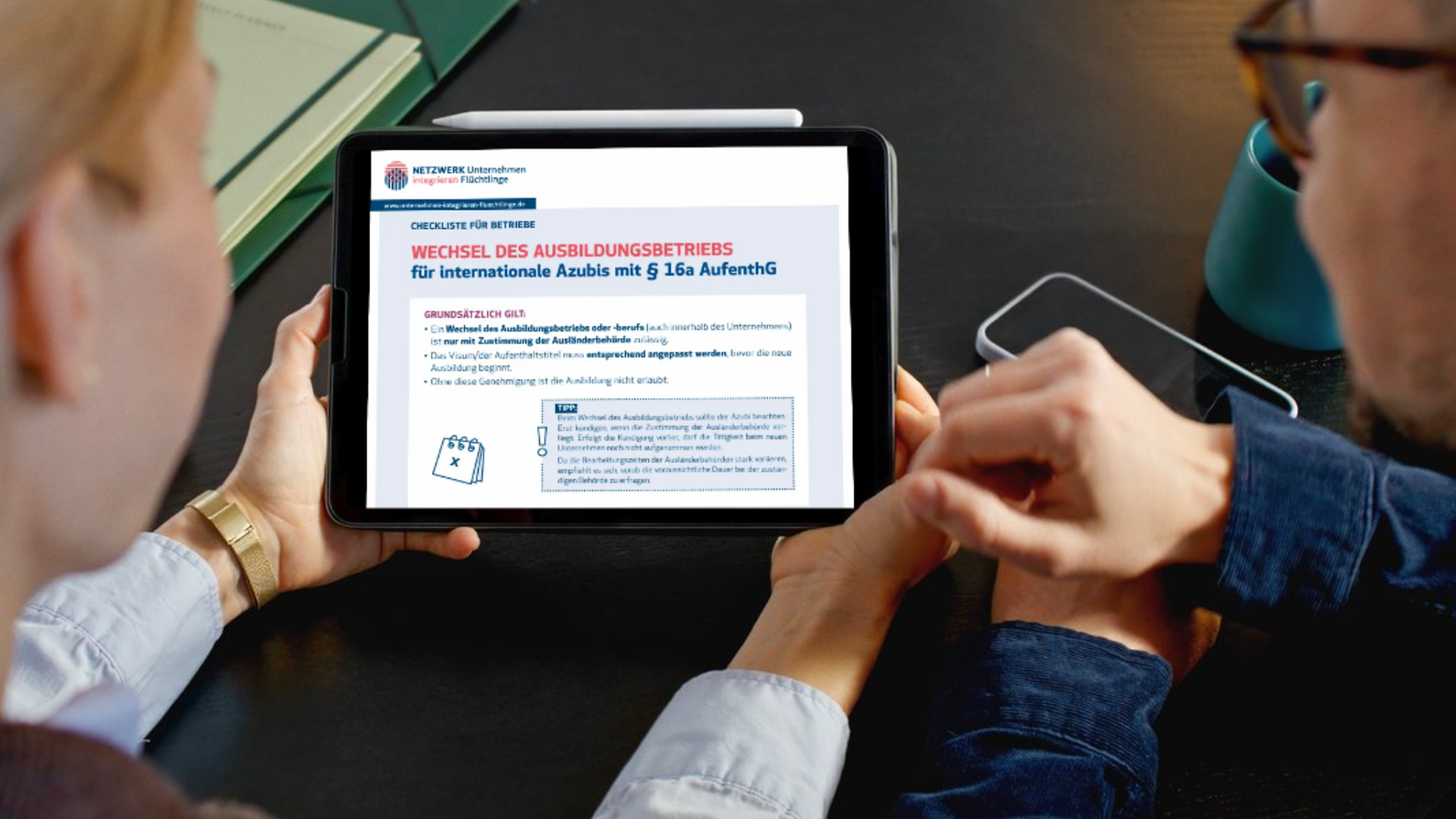 Zwei Personen schauen auf eine Tablet, auf dem eine Checkliste geöffnet ist