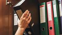Aktenordner wird aus Schrank genommen. 