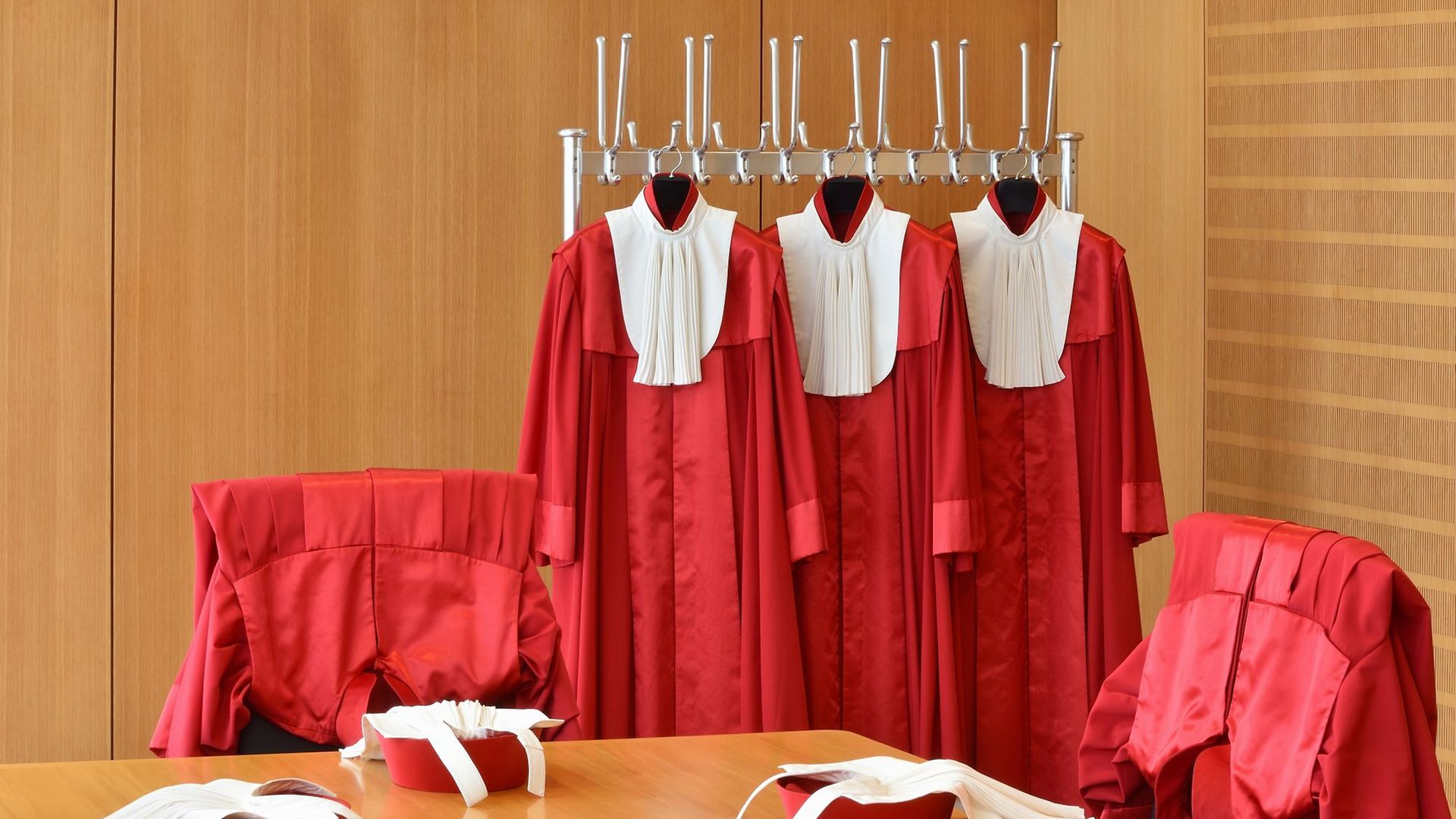 Rote Richterroben hängen an einer Garderobenstange, Barette liegen auf dem Tisch