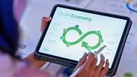 Frau hält Tablet mit Kreislaufwirtschafts-Symbol 