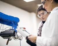 Zwei Ingenieurinnen an einem Roboterarm