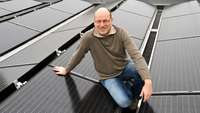 Mann sitzt auf Solarmodulen