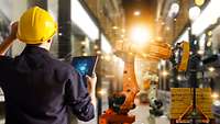 Mann überprüft Roboter per Tablet