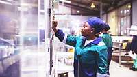 Afrikanerin bedient Fertigungssteuerung in einer Fabrik