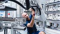 Man schraubt an einem Roboterarm