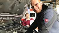 Integrationsscout Schmauder beugt sich über eine Motorhaube