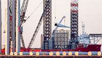 Teile von Windkraftanlagen werden mit Kränen auf einen Frachter verladen