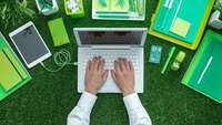 Ein Laptop ist umringt von grünen Büroutensilien