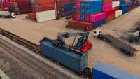 Ein kleiner Kranwagen verlädt Container auf Bahnwaggons