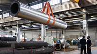 Stahlbau: Großes Stahlrohr hängt in einer Werkhalle am Kran